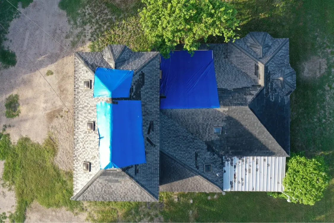 Storm damaged roof covered with blue tarps in Mission